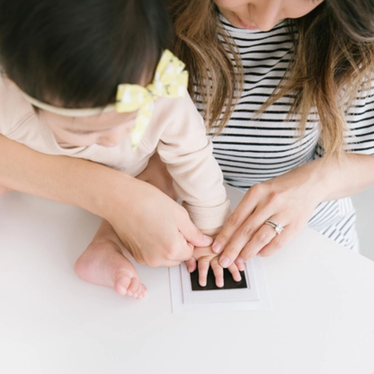 Close-up view of a clean-touch ink pad showing how the baby’s hand presses on the top surface without touching the ink.