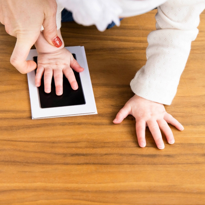 Parents gently press a baby’s hand onto a clean-touch ink pad to create a mess-free footprint.