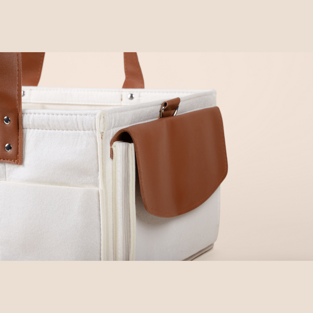 Cream tote bag with brown leather accents on a beige background