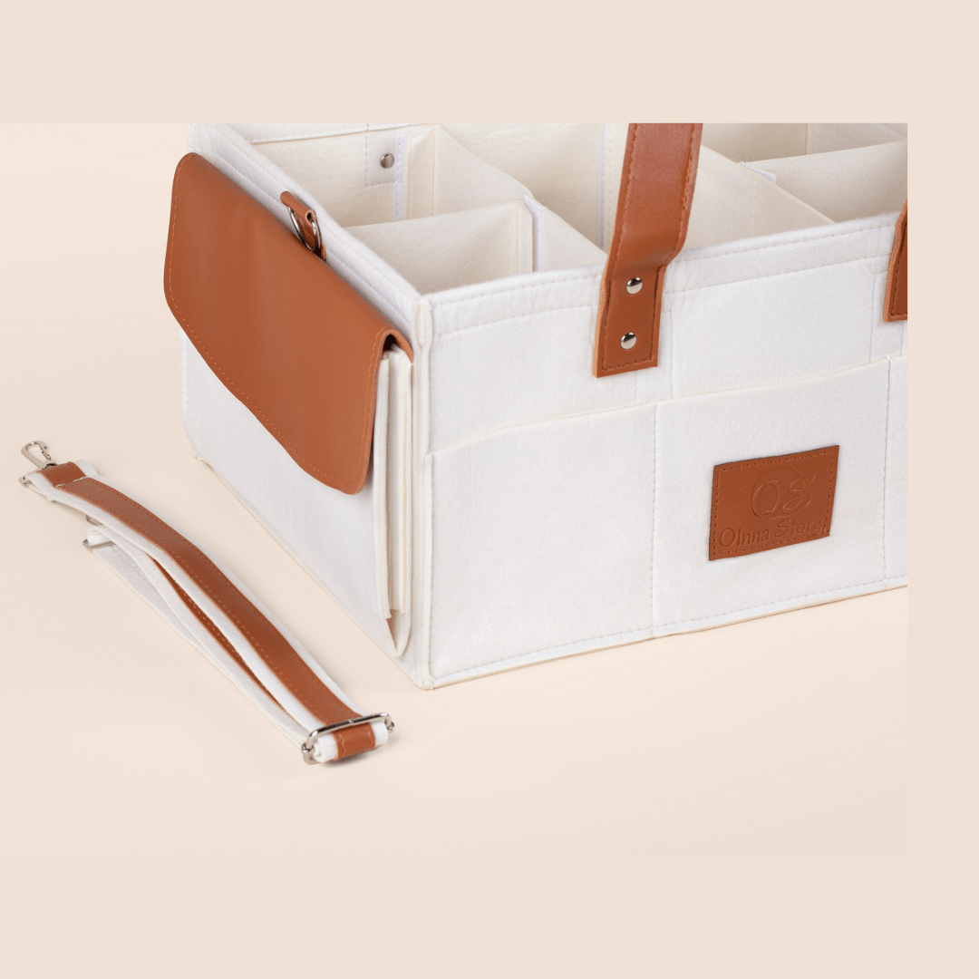 Cream storage bin with brown leather straps on a beige background