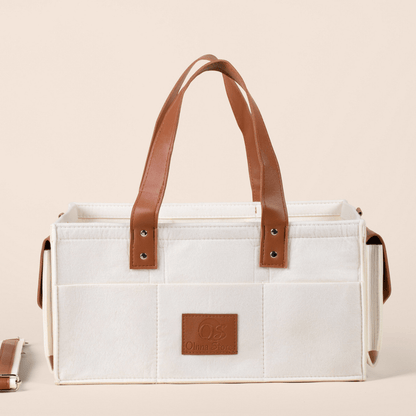 Cream tote bag with brown leather handles and accents on a beige background